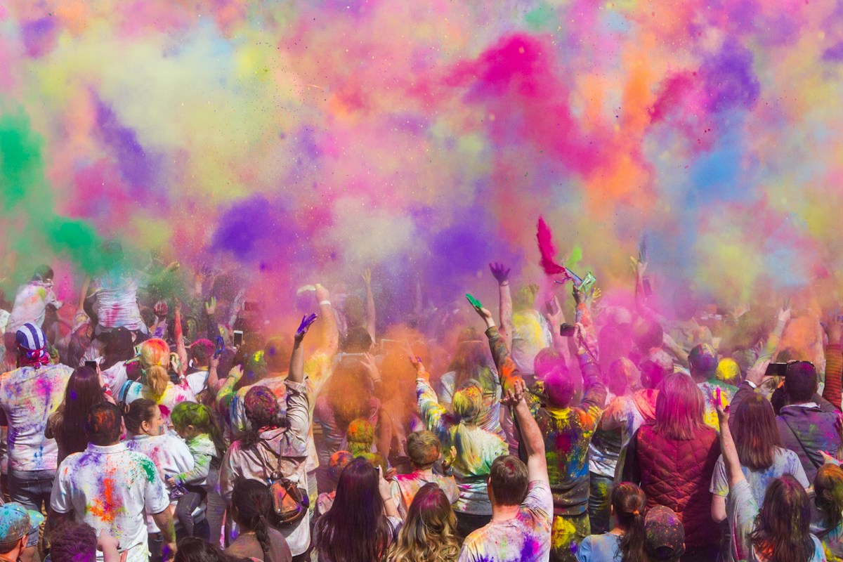 Tłum ludzi rzucających kolorowy proszek podczas święta Holi